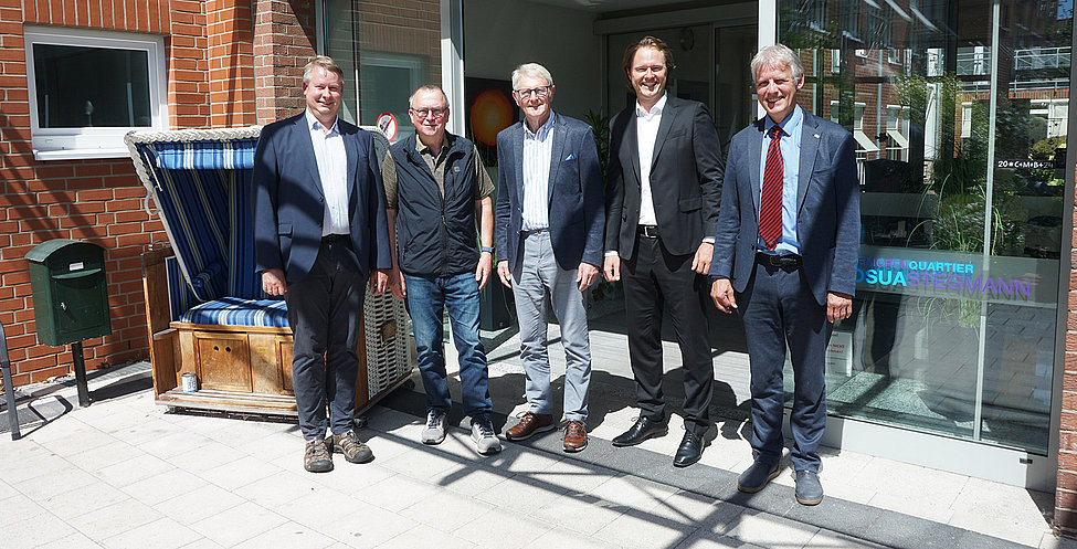 Fünf Männer stehen lächelnd nebeneinander und schauen in die Kamera.